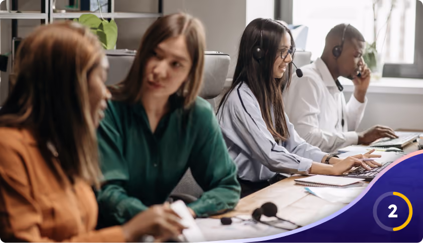 Four diverse customer support staff wearing headsets working together in a modern office.