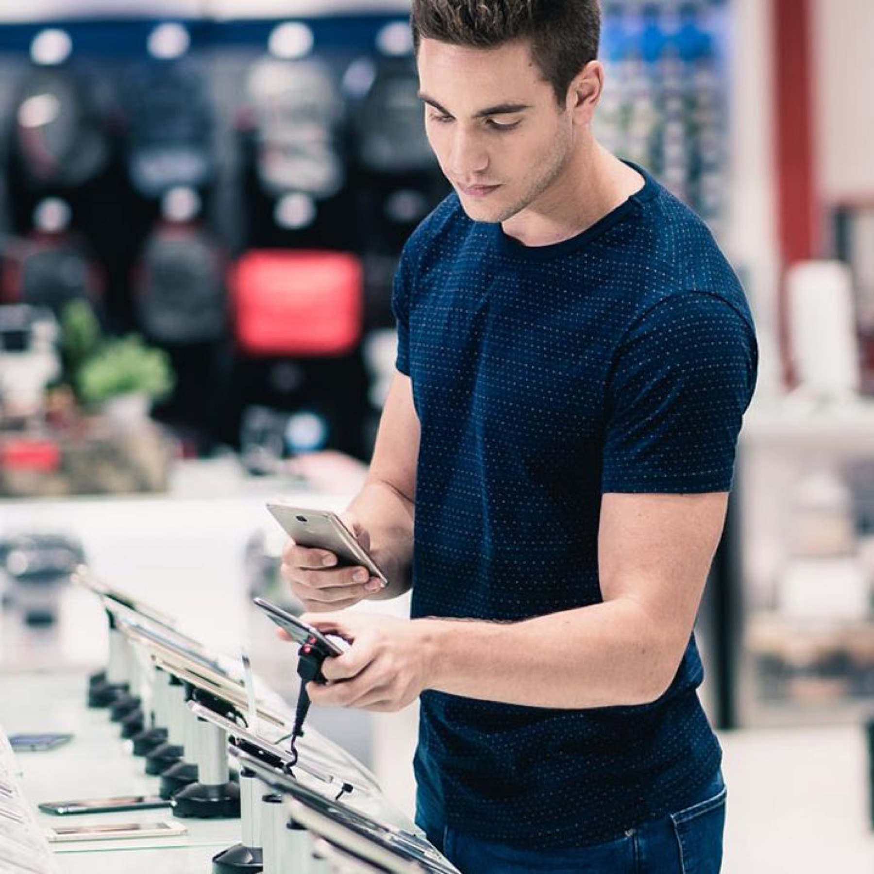 Shopper comparing mobile phones on an electronics store display