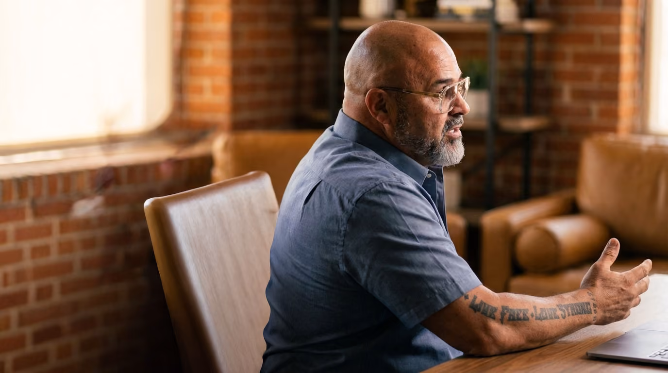 Dr. Kirk Elliott in a blue shirt, talking with someone in a brick-walled office