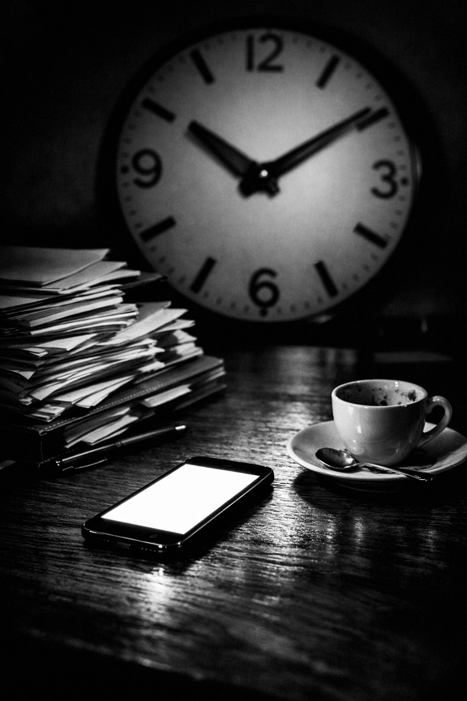 Professional desk at night with a glowing phone and clock, representing the stress of daily content creation.