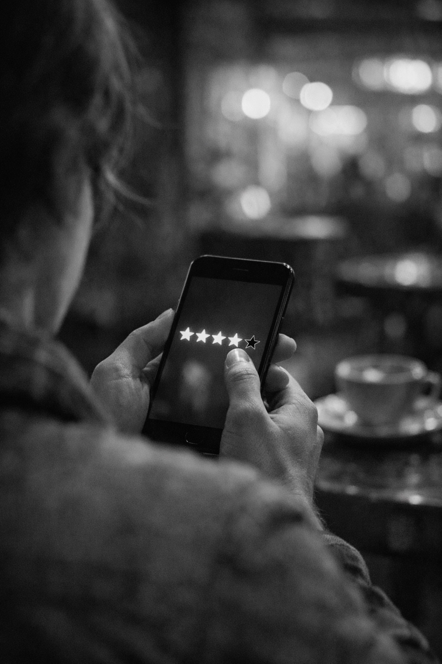 Close-up of a person using a smartphone to view star ratings and manage online customer feedback.