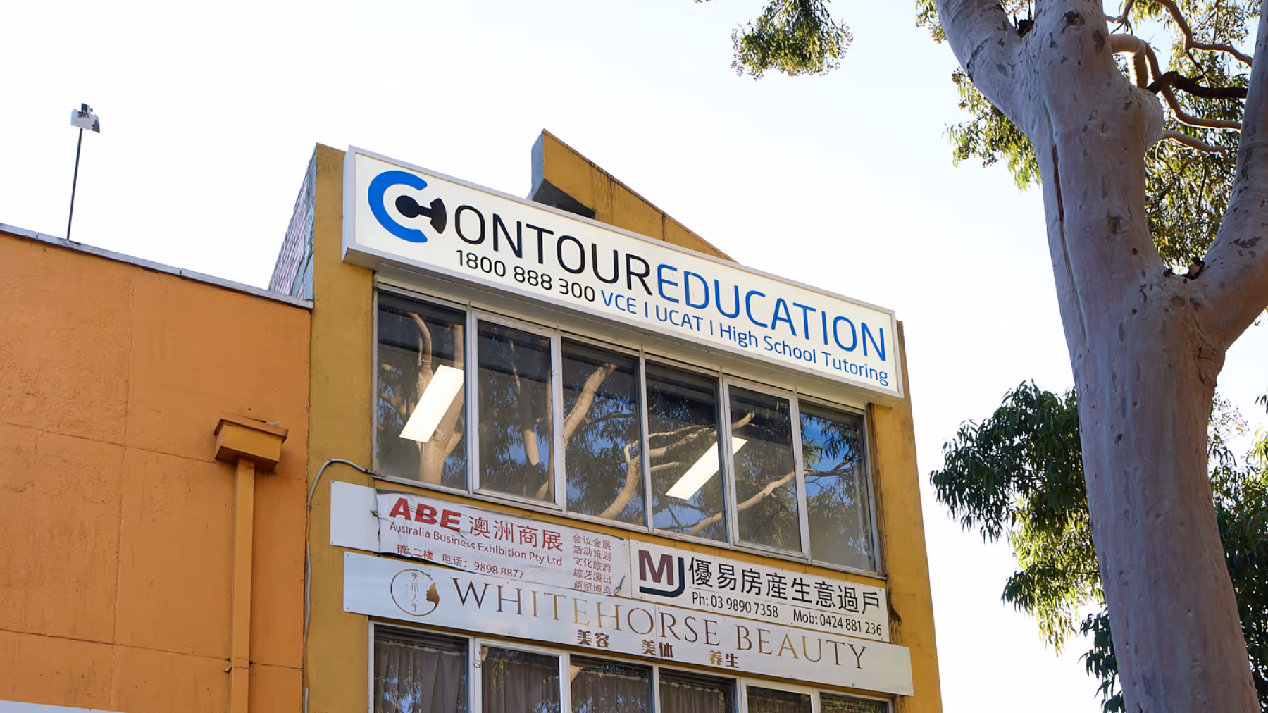 Building facade with signs for Contour Education tutoring, Australia Business Exhibition, MJ real estate, and Whitehorse Beauty.