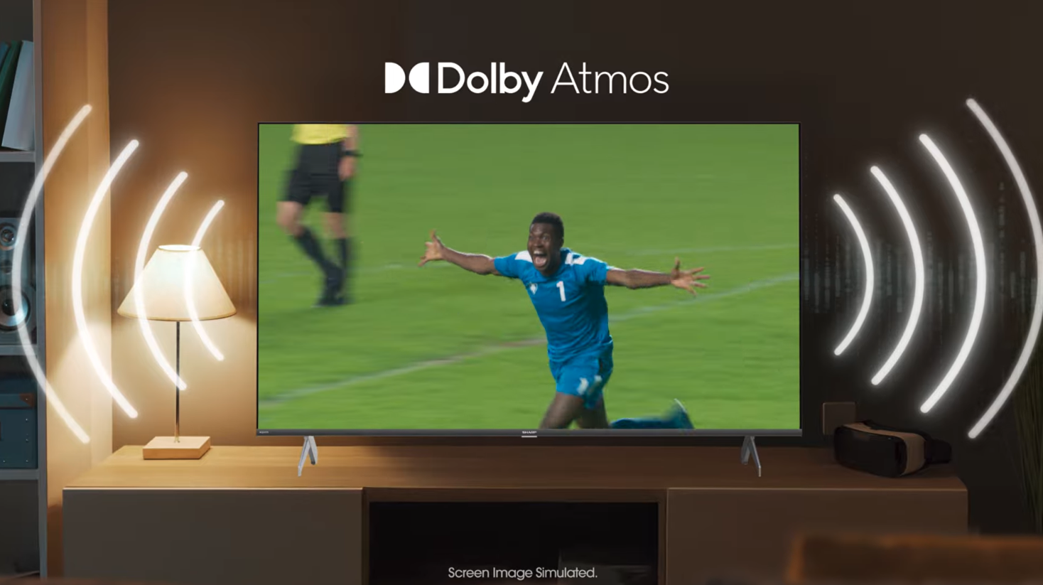 Television on a wooden stand showing a soccer player celebrating, with Dolby Atmos sound waves illustrated around it.