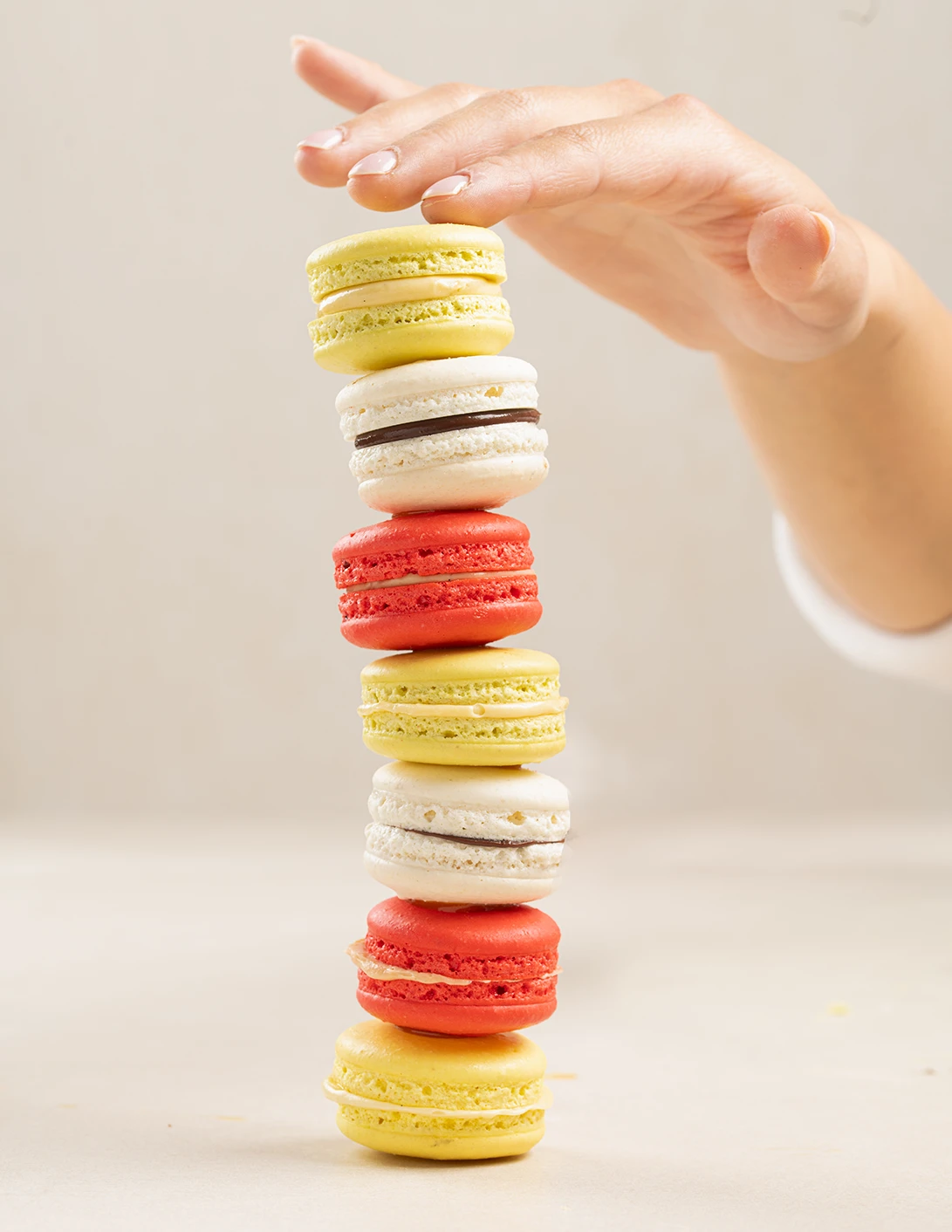 Hand stacking colorful French macarons