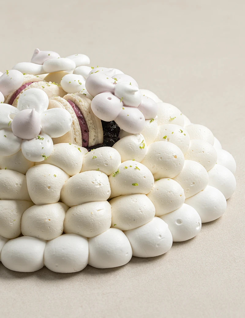 Blueberry Pavlova with baked meringue, vanilla custard cream, blueberry jam, blueberry macaron, and meringue flowers.