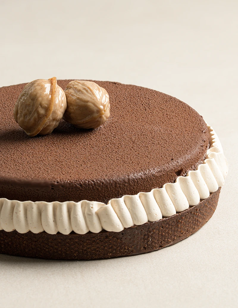 Nut Noir dessert with chocolate velvet coating, nut mousse, and praline walnuts on top.