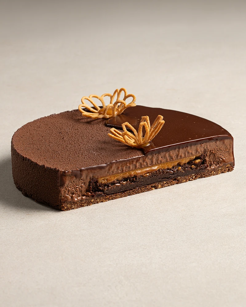 Chocolate Explosion cut in half showing chocolate praline crunch base, nemesis cake, hazelnut praline, and chocolate mousse layers.
