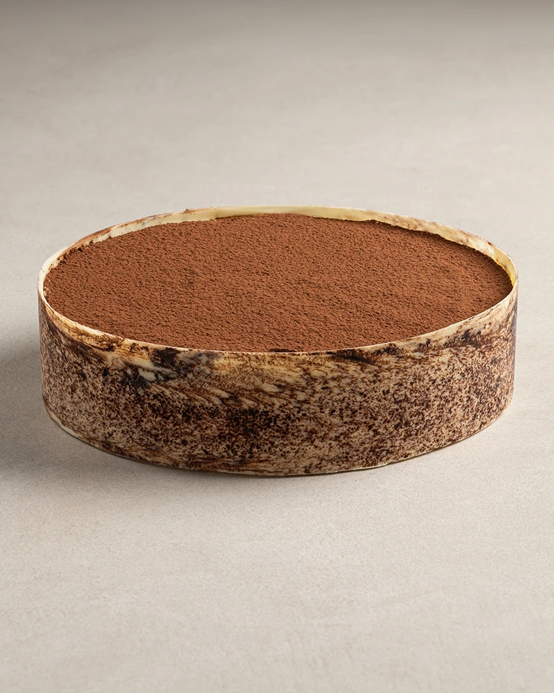 Whole Classic Tiramisu cake with espresso-soaked ladyfingers, vanilla cream, and cocoa powder topping.