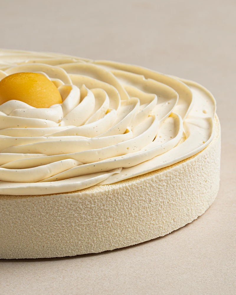 Exotic Cheesecake with white chocolate velvet spray, vanilla Chantilly cream, and passion fruit marmalade.