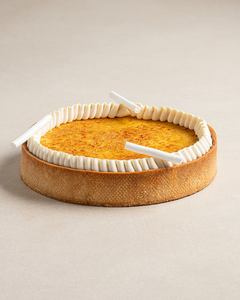 Whole Signature Crème Brûlée tart with almond base, creamy filling, caramelized sugar top, and Chantilly cream.