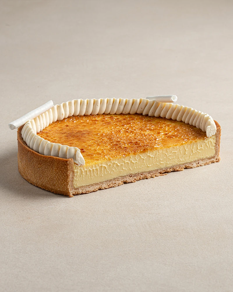 Signature Crème Brûlée dessert cut in half showing almond tart base and creamy crème brûlée filling layers.