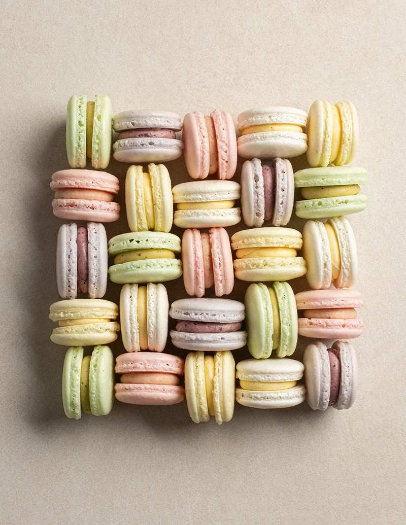 Pastel macarons cut in half showing assorted flavored fillings and smooth shells.