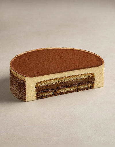 Classic Tiramisu cut in half showing espresso-soaked ladyfingers, chocolate crémeux, and vanilla cream layers.