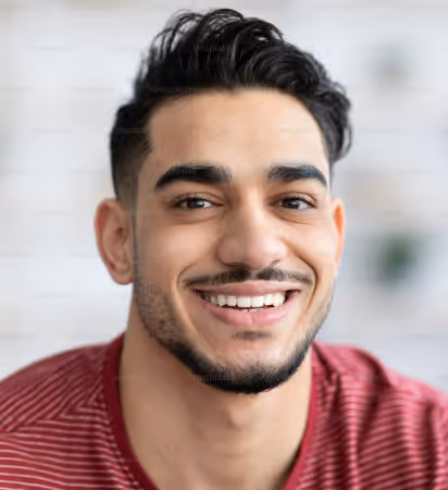 Smiling young man with dark hair and beard wearing a red striped shirt.