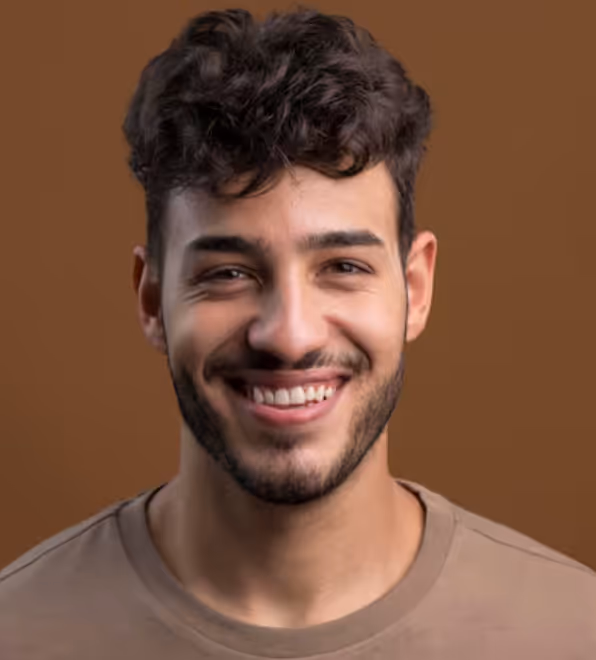 Smiling young man with curly dark hair, beard, and brown shirt against a brown background.