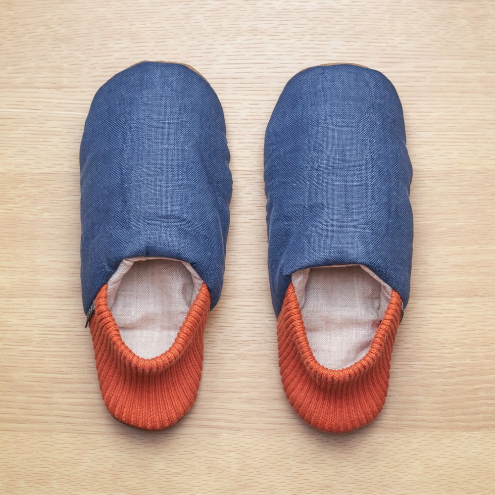 The same blue and orange TopDrawer slippers photographed from above on a light wood table.