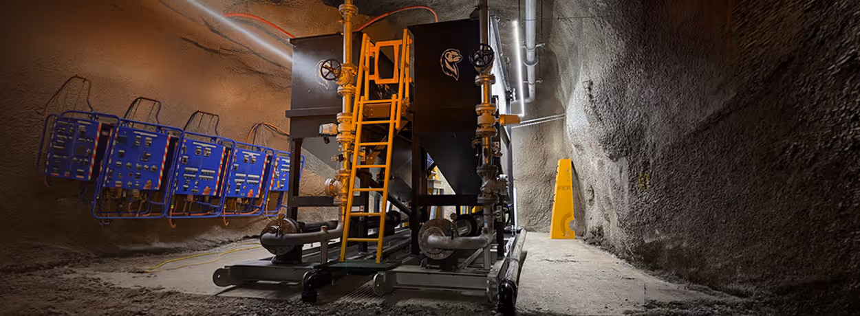 Workers in high-visibility clothing installing a long pipeline on red soil with an orange Kubota skid steer loader and white truck in a semi-arid landscape.