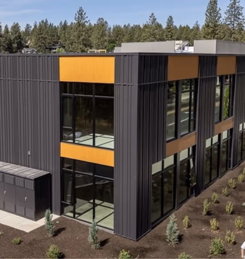 Modern two-story commercial building with dark vertical paneling and large glass windows accented by horizontal yellow panels.