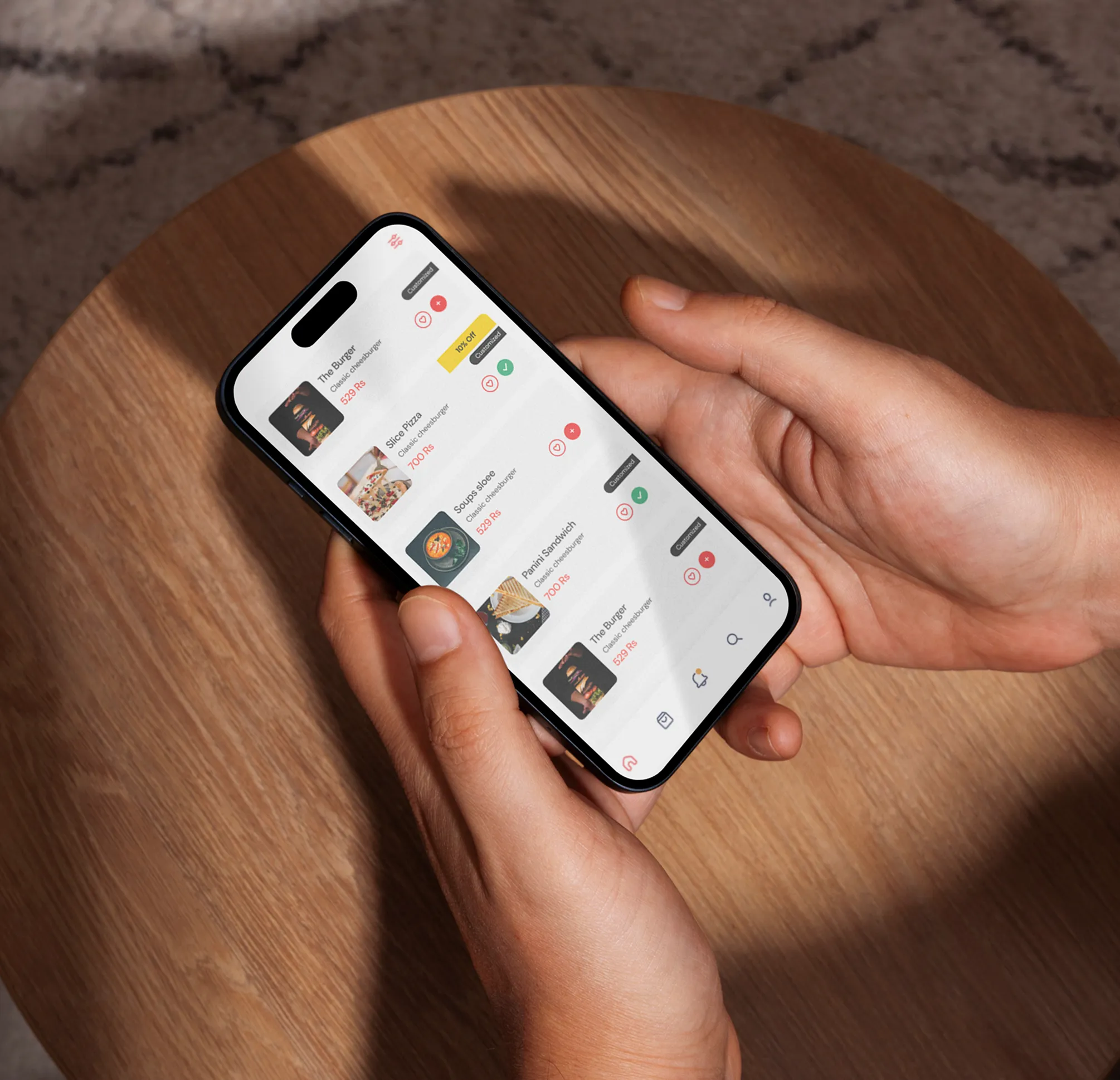 Person holding a smartphone displaying a food ordering app with a list of items including burgers, pizza, soup, and sandwich along with prices and customization options.