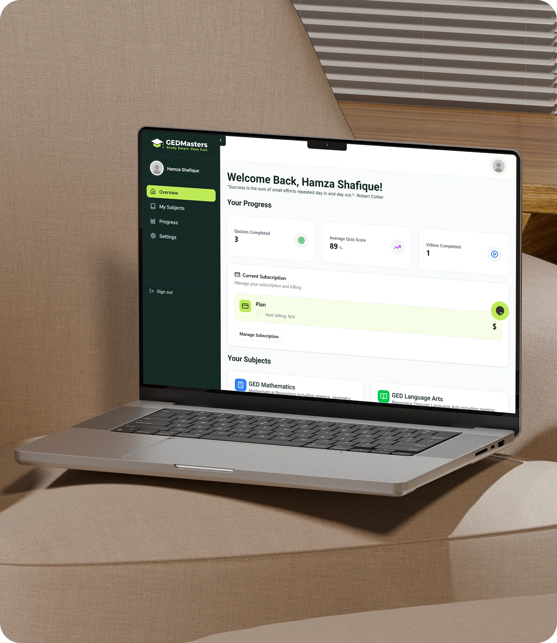 Open laptop on beige cushioned chair showing GEDMasters dashboard with progress in quizzes, average quiz score, videos completed, and current subscription details.
