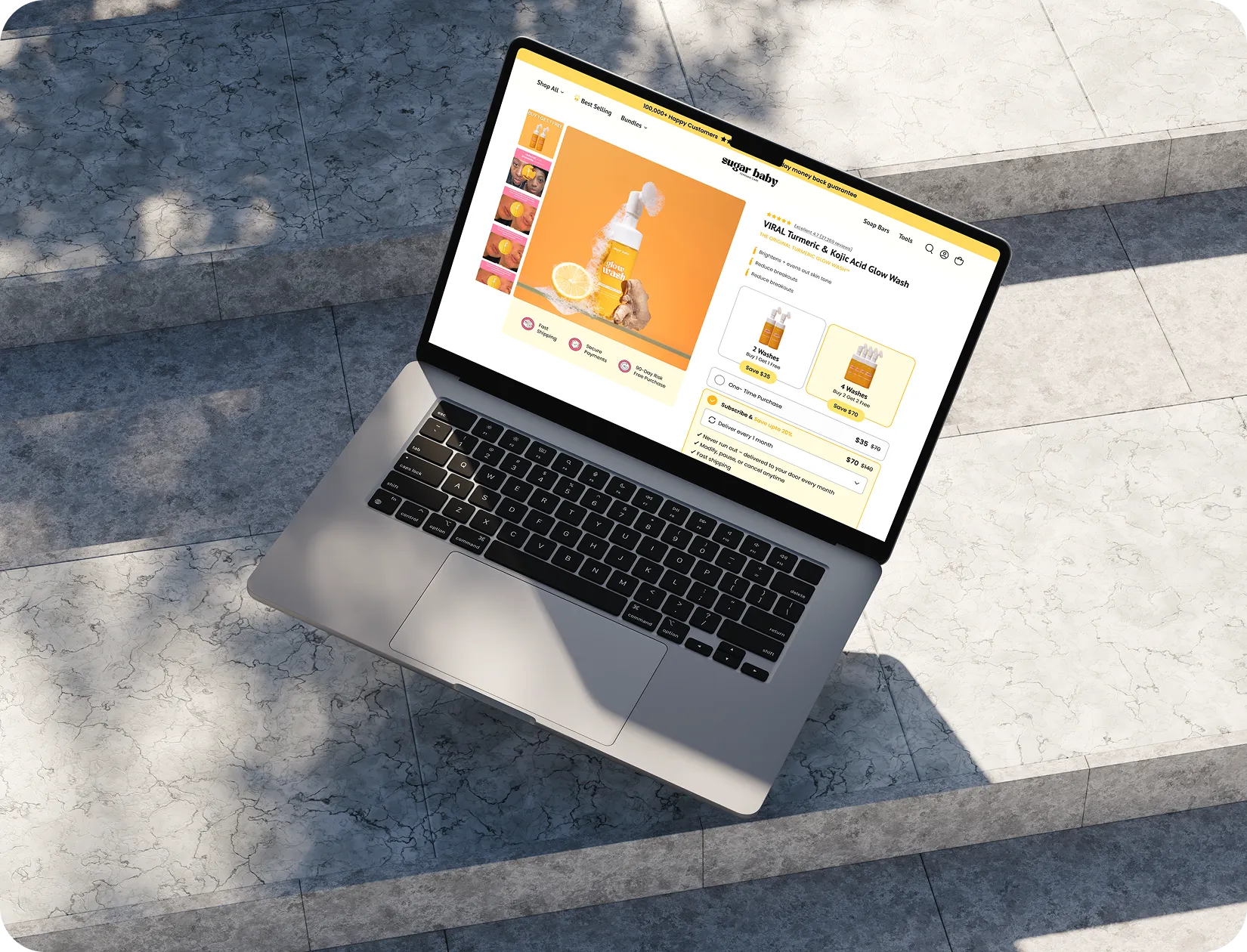 Open laptop on steps displaying Sugar Baby website selling a turmeric and kojic acid glow wash.