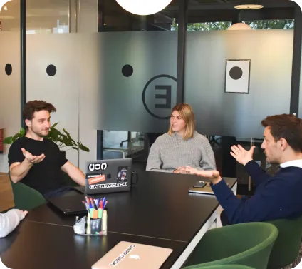 Three people having a video conference meeting around a table in a modern office.