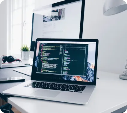 Open laptop on desk showing code editor with programming code in a modern workspace.