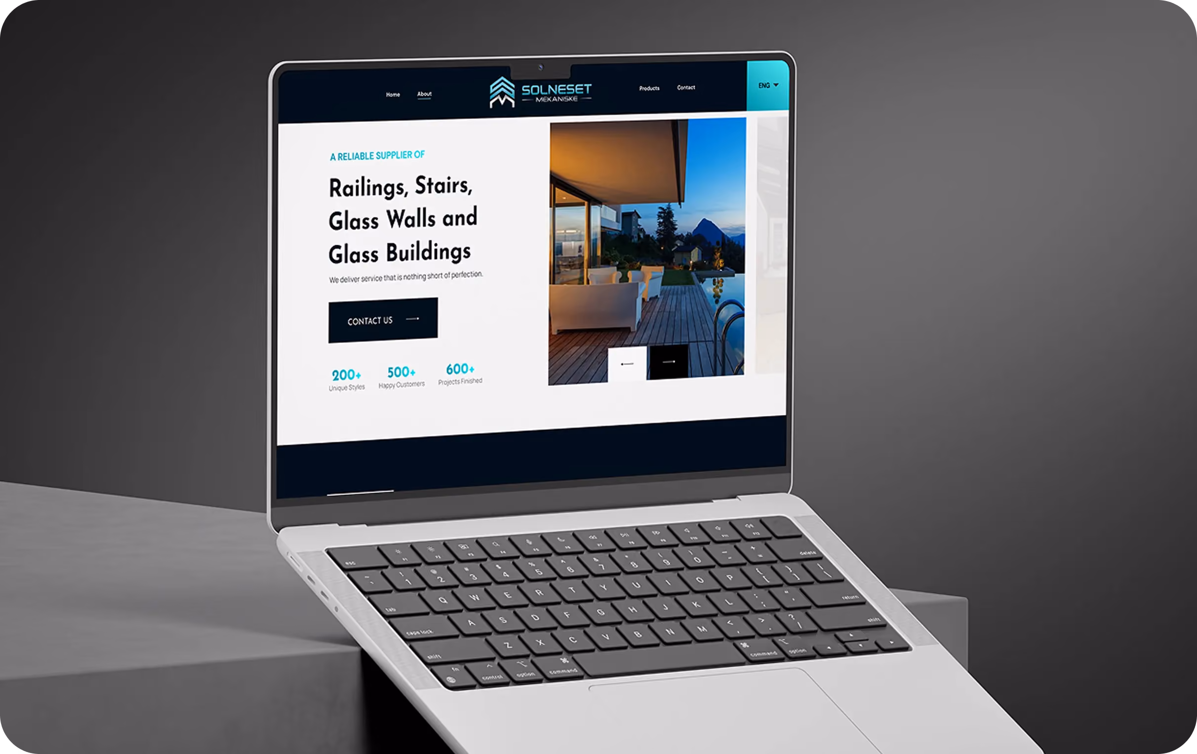 Laptop displaying a website offering railings, stairs, glass walls, and buildings with a contact button.