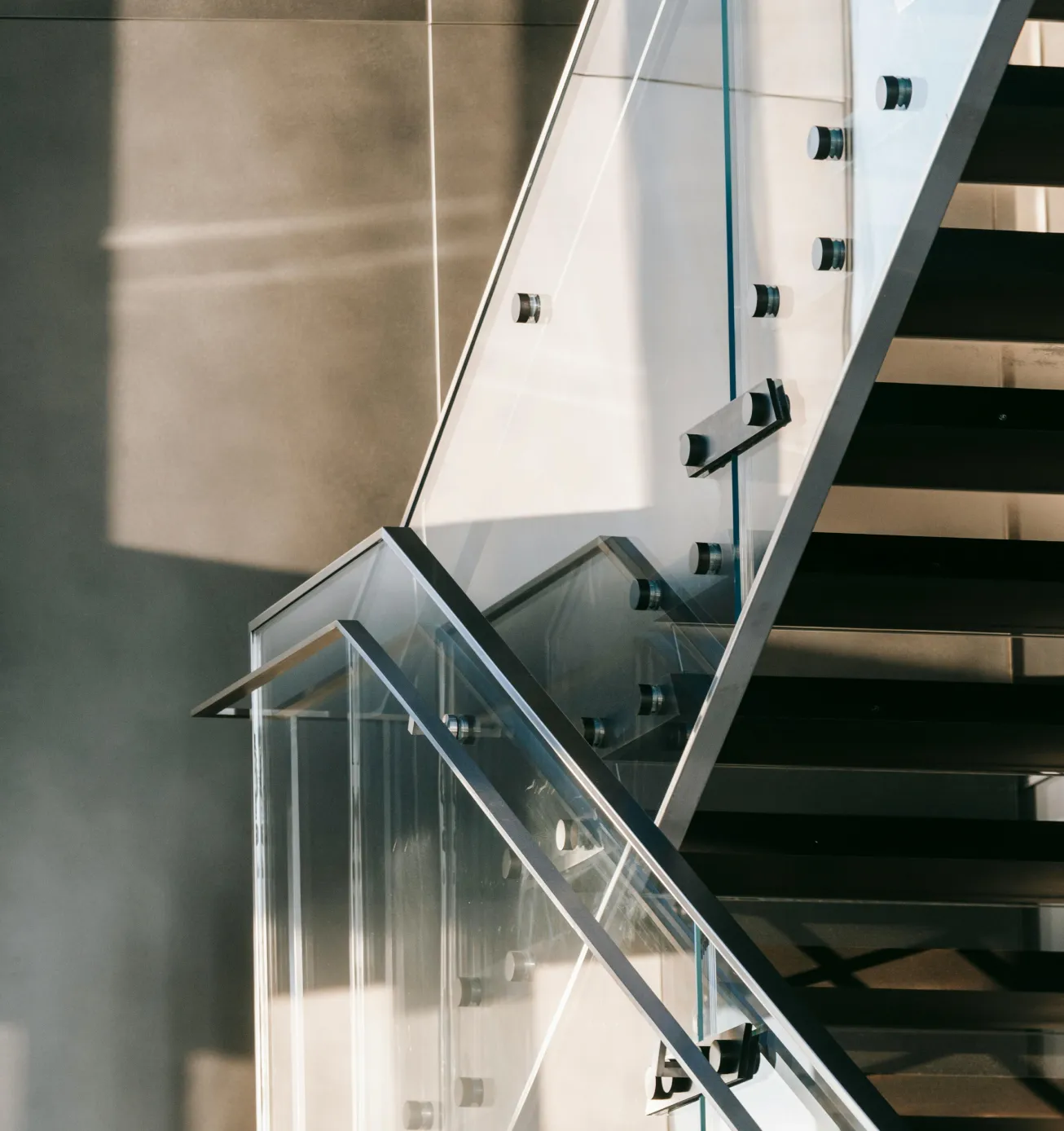 Spiral staircase with wood steps and curved glass railing in a modern interior space.