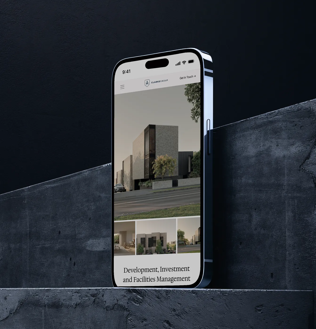 Smartphone displaying Clarke Group website with modern building images and services in development and management.