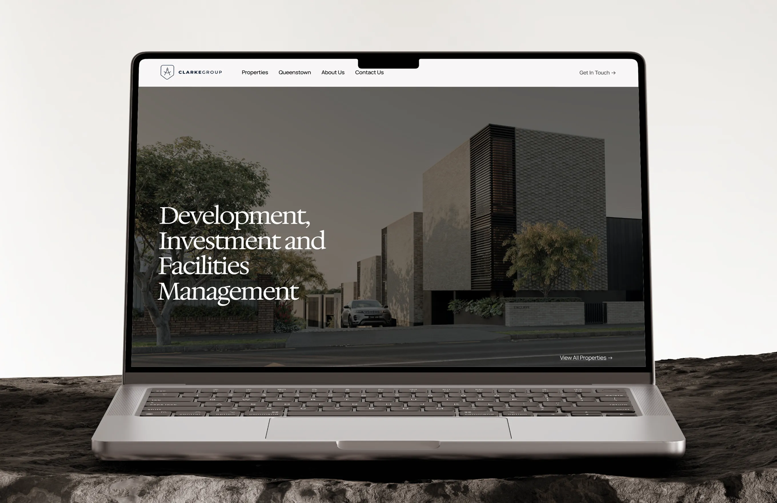 Laptop screen showing Clarke Group website with text on real estate development and management.