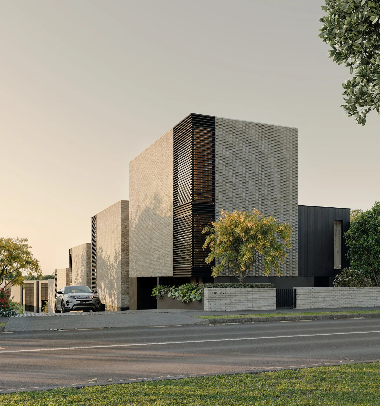Modern brick townhouse complex with black accents, trees, and a silver SUV parked in driveway.