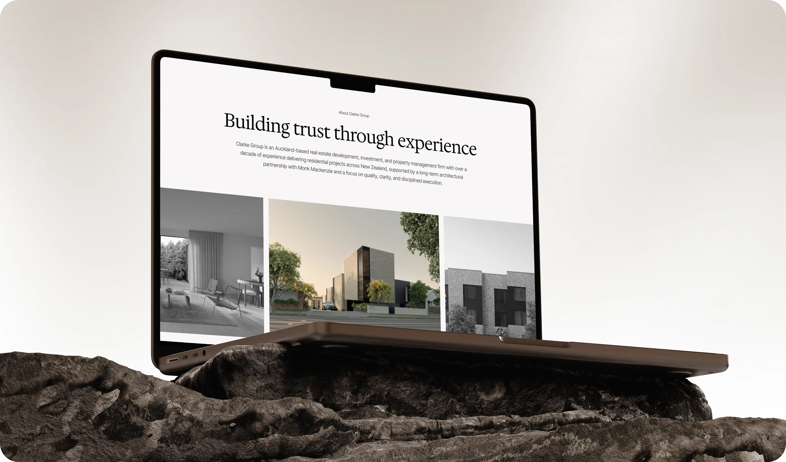 Laptop on rocky surface displaying real estate website about Clarke Group’s experience and projects.