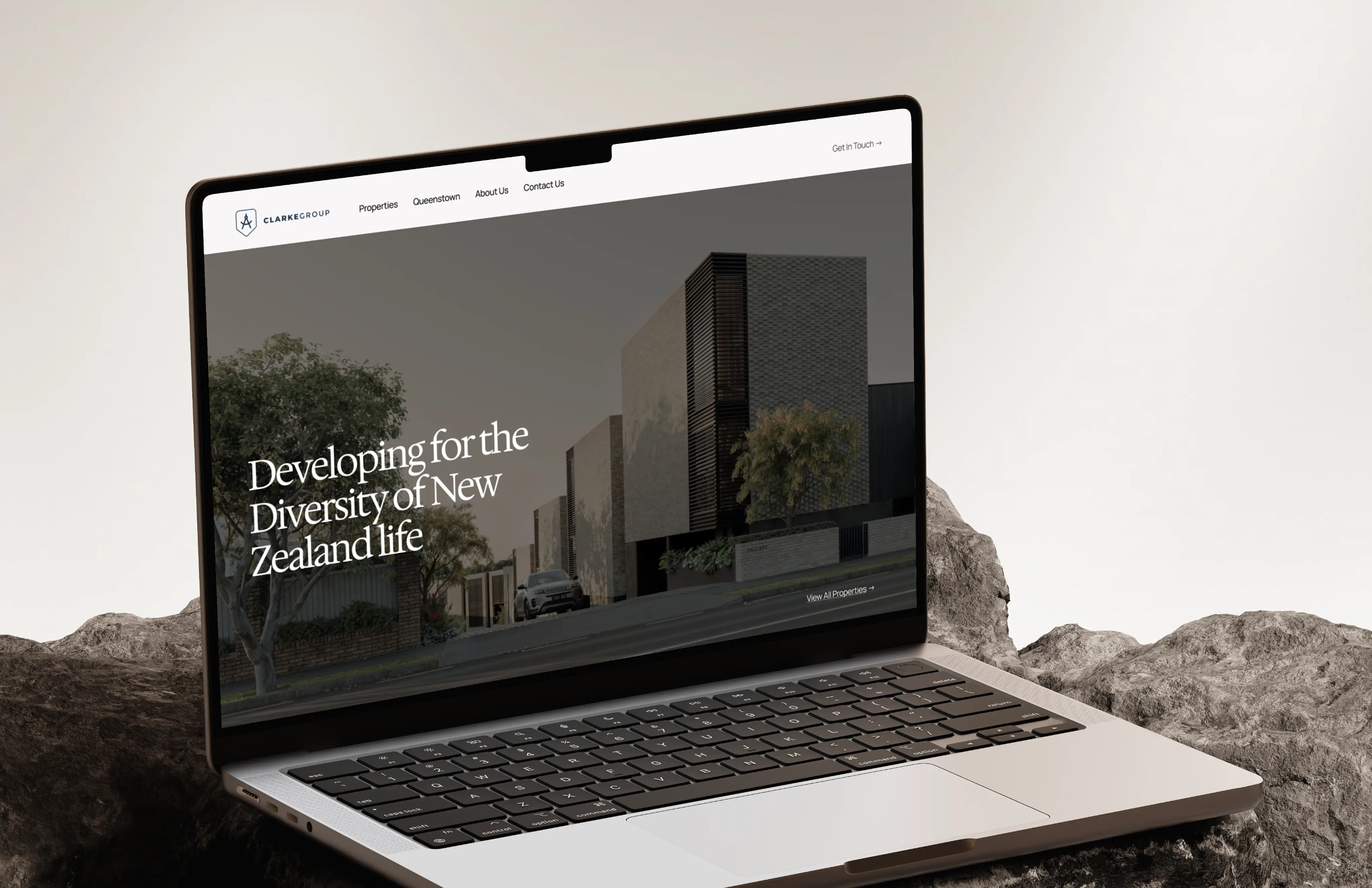 Laptop screen shows Clarke Group website with modern buildings and text about New Zealand life.