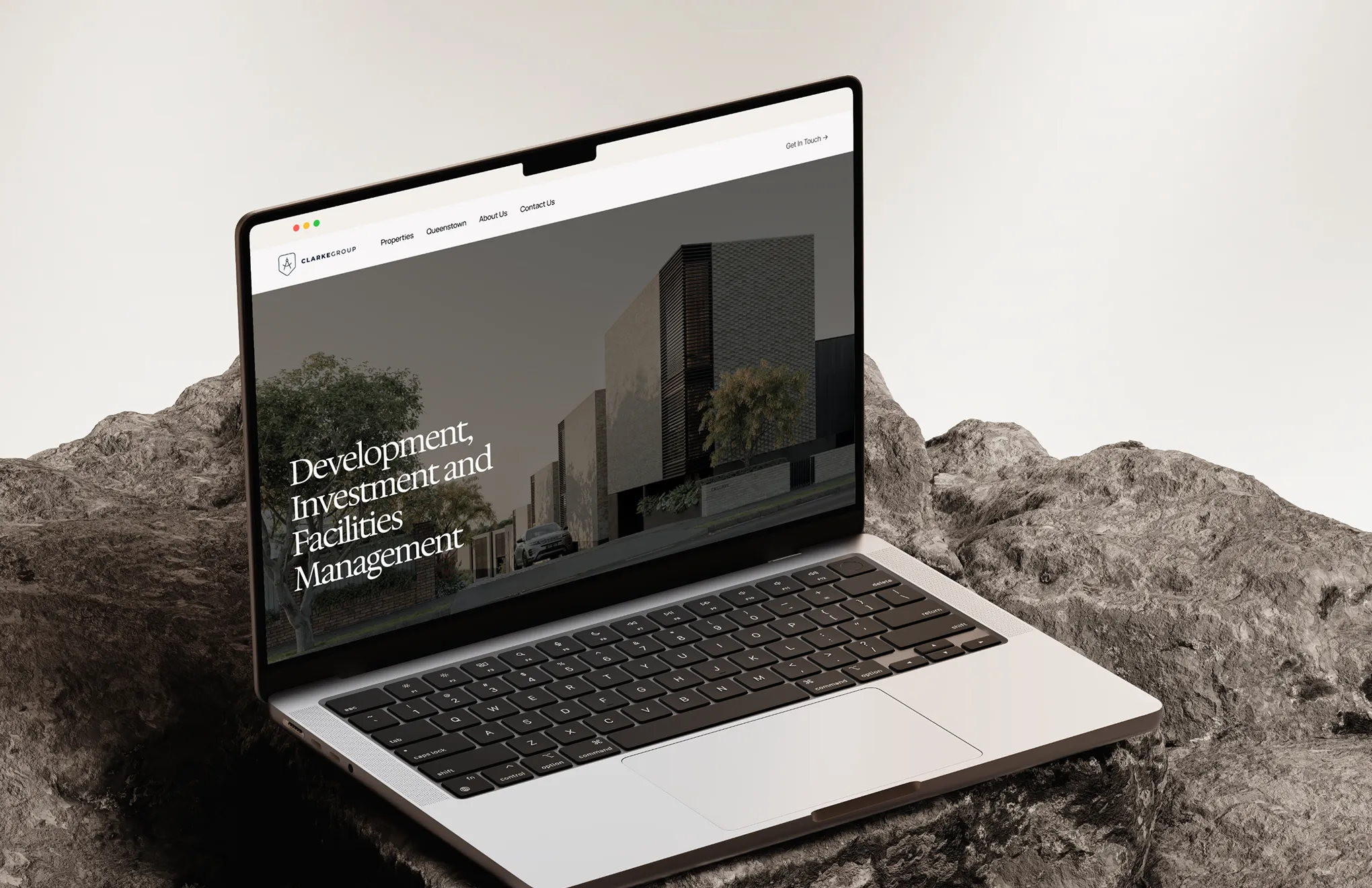Laptop screen shows Clarke Group website with modern buildings and text about New Zealand life.