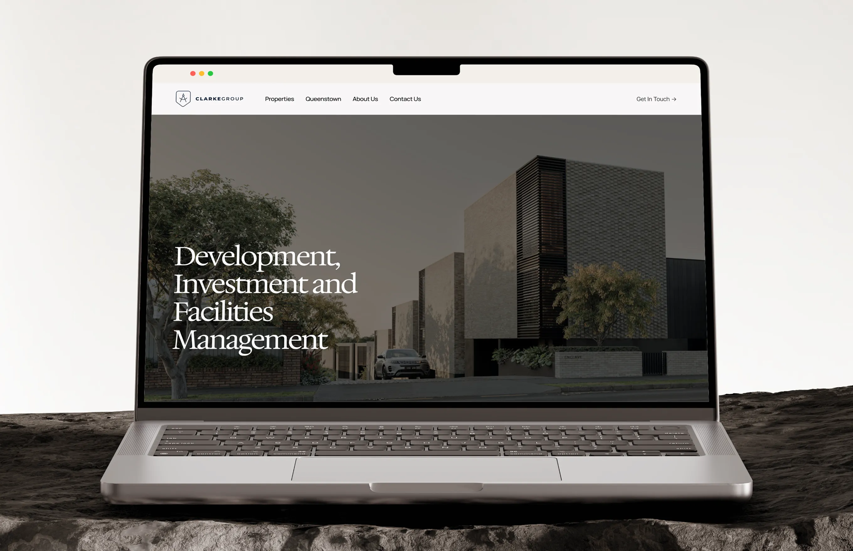 Laptop screen showing Clarke Group website with text on real estate development and management.