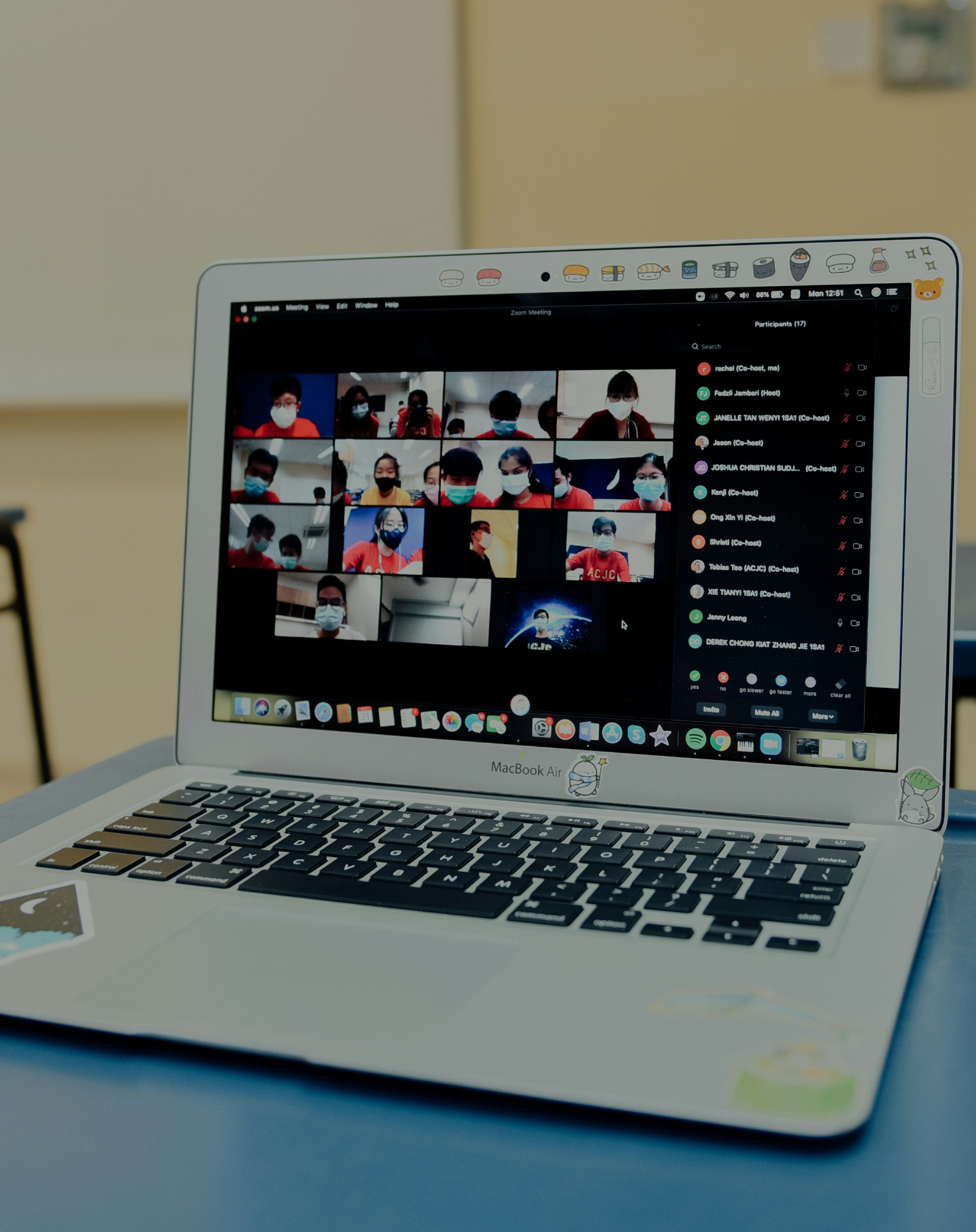 MacBook Air laptop showing a Zoom meeting with people wearing face masks in video thumbnails.