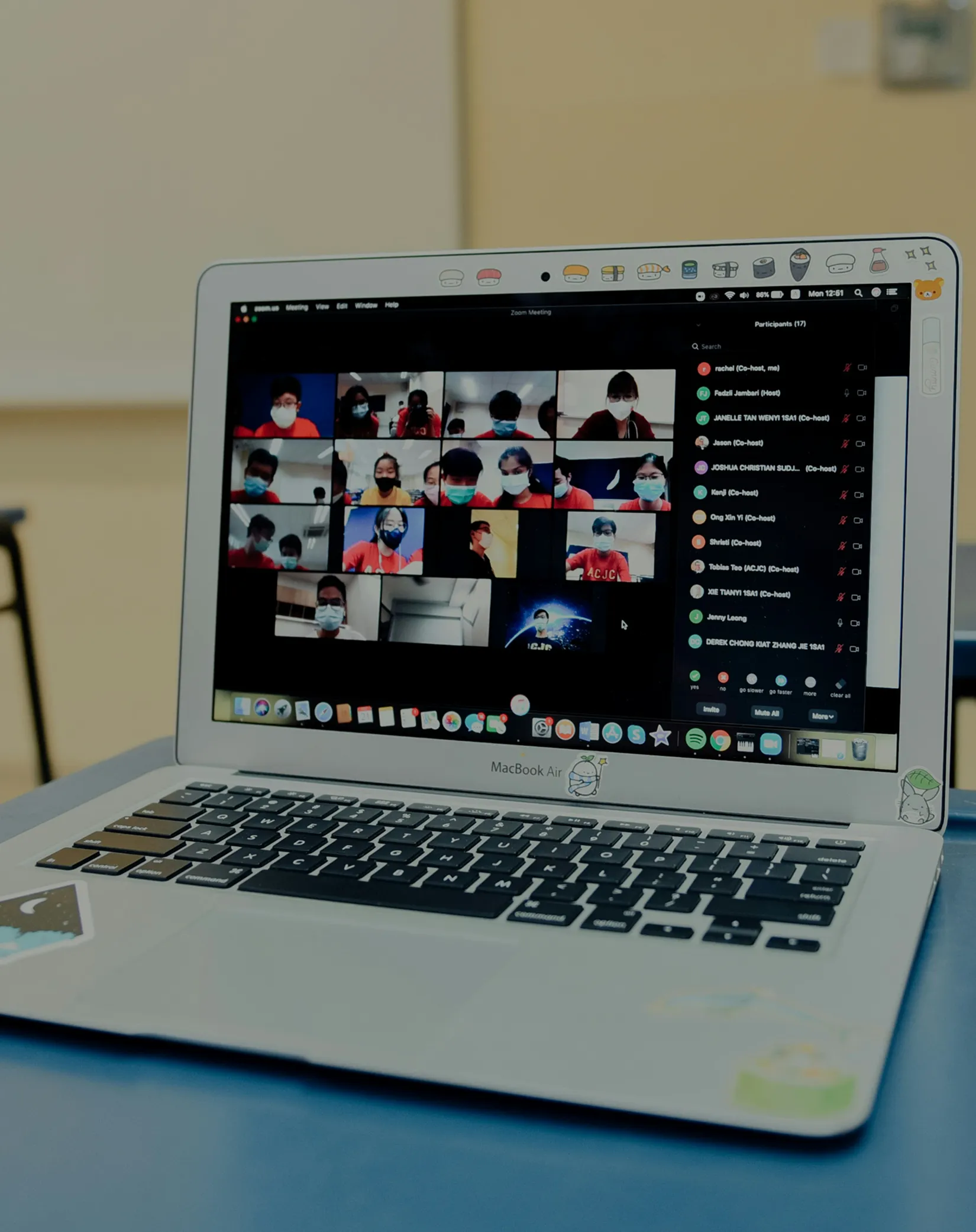 MacBook Air laptop showing a Zoom meeting with people wearing face masks in video thumbnails.