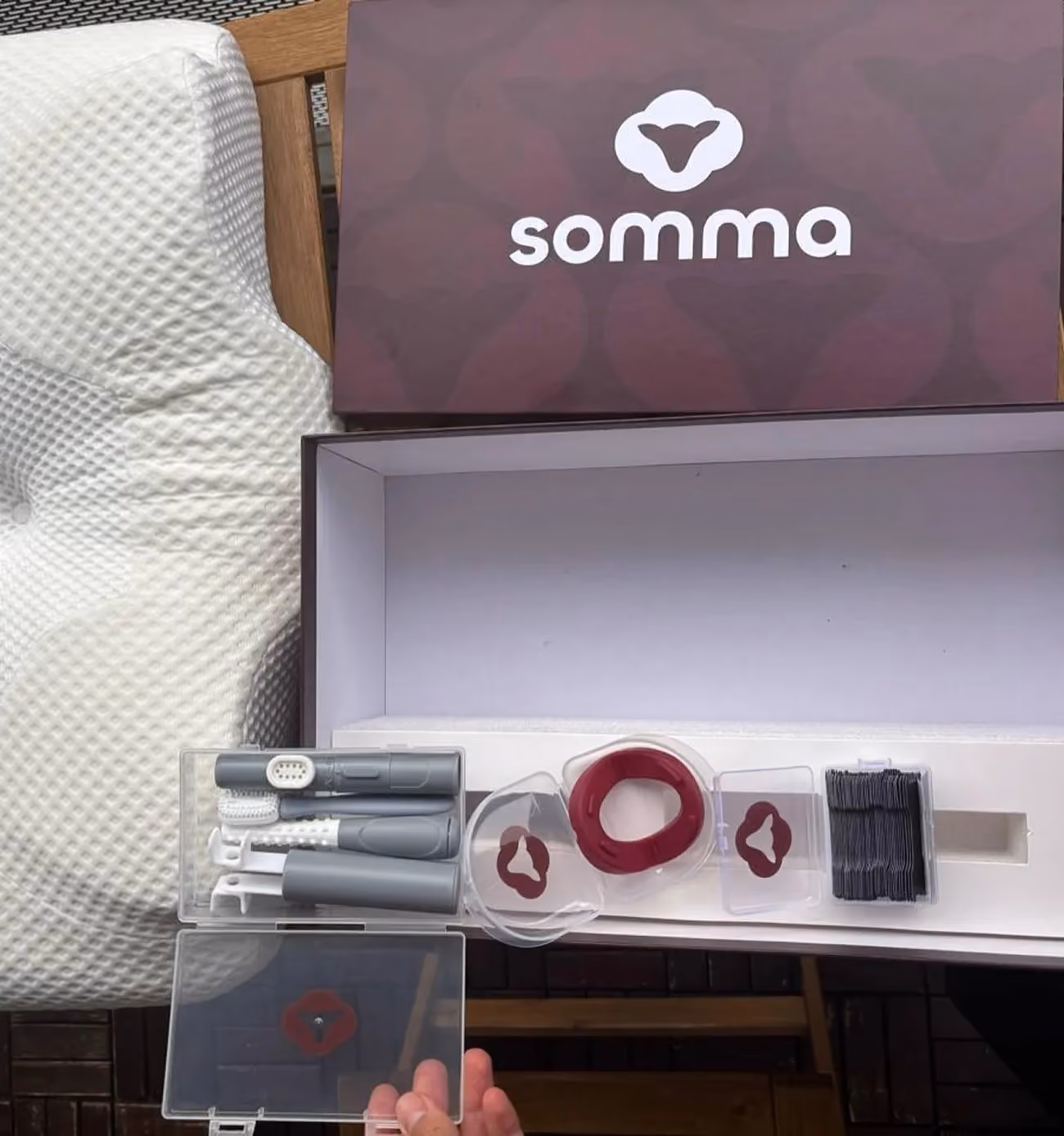 Open Somma box with dental care tools, red ring device, brushes, and black floss picks inside.