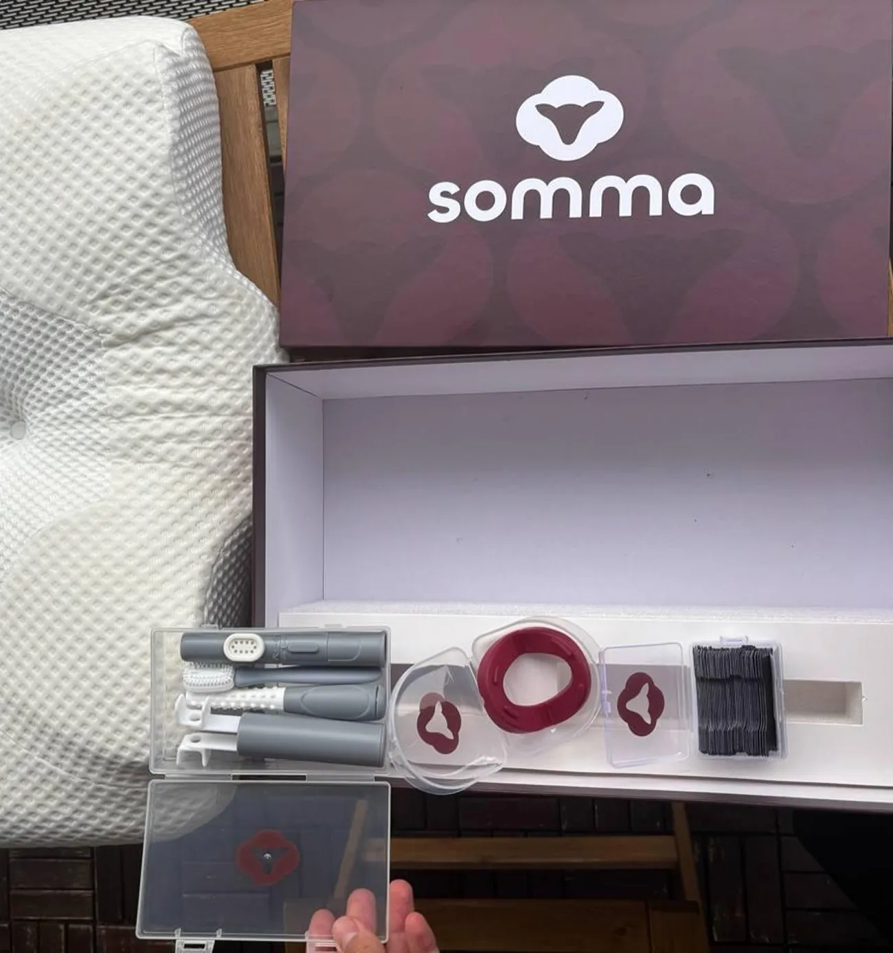 Open Somma box with dental care tools, red ring device, brushes, and black floss picks inside.
