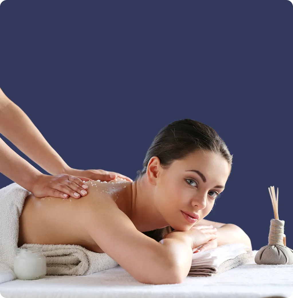 Woman receiving a back massage with exfoliating salt on her skin in a spa setting.
