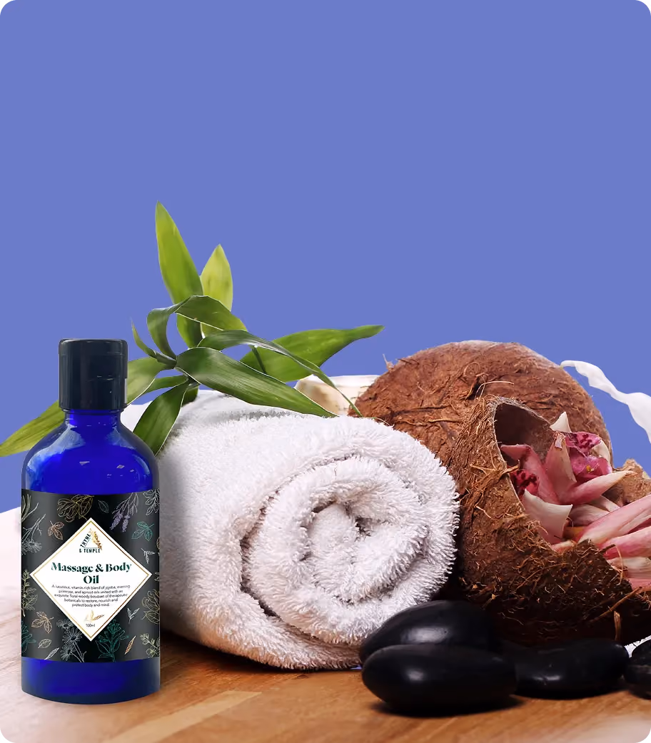 Massage and body oil bottle beside a rolled white towel, green leaves, coconut shell, and black stones.