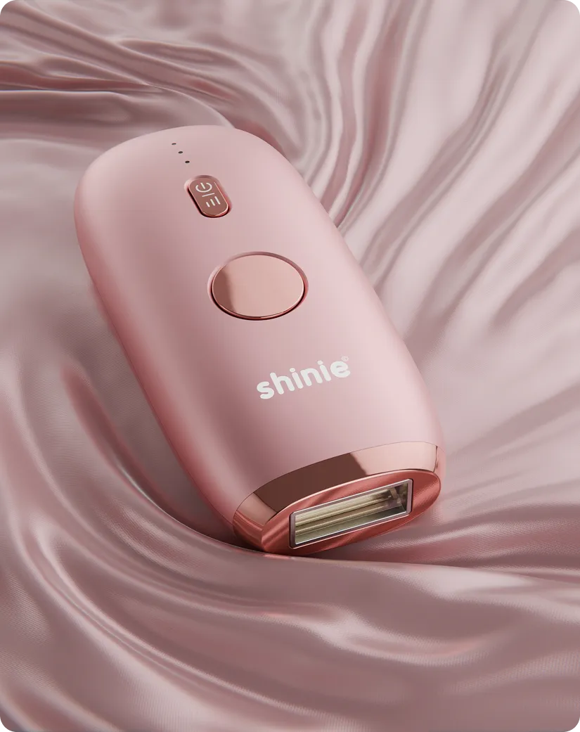 Pink electronic device labeled 'shinie' resting on soft, pink satin fabric.
