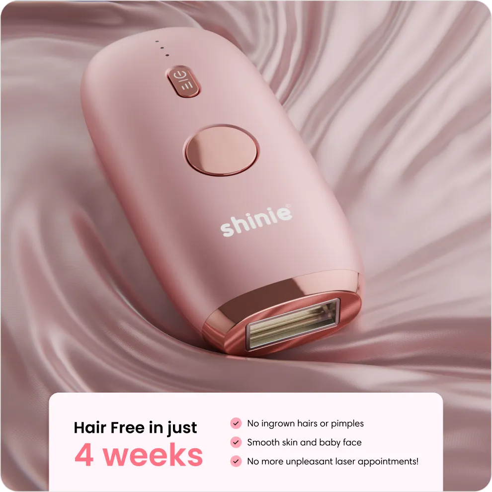 Pink Shinie laser hair removal device on silky pink fabric with 4 weeks hair-free benefits list.