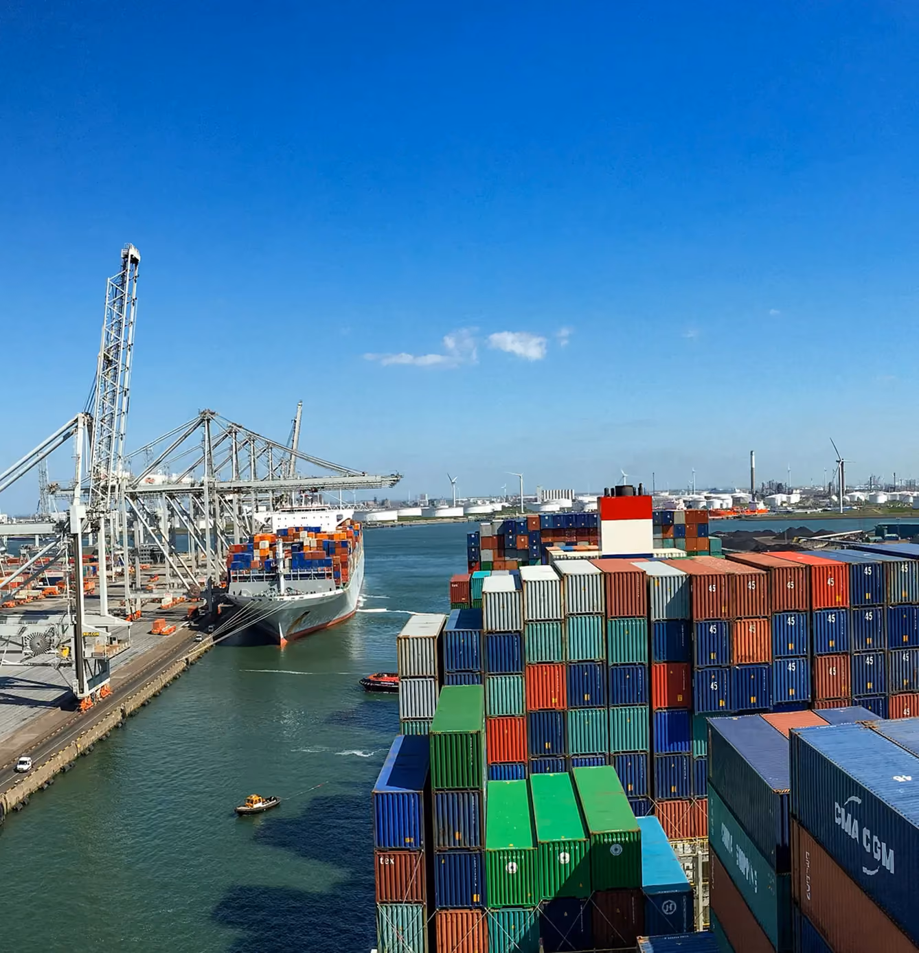 Large cargo ships docked at a port with numerous colorful shipping containers stacked high.