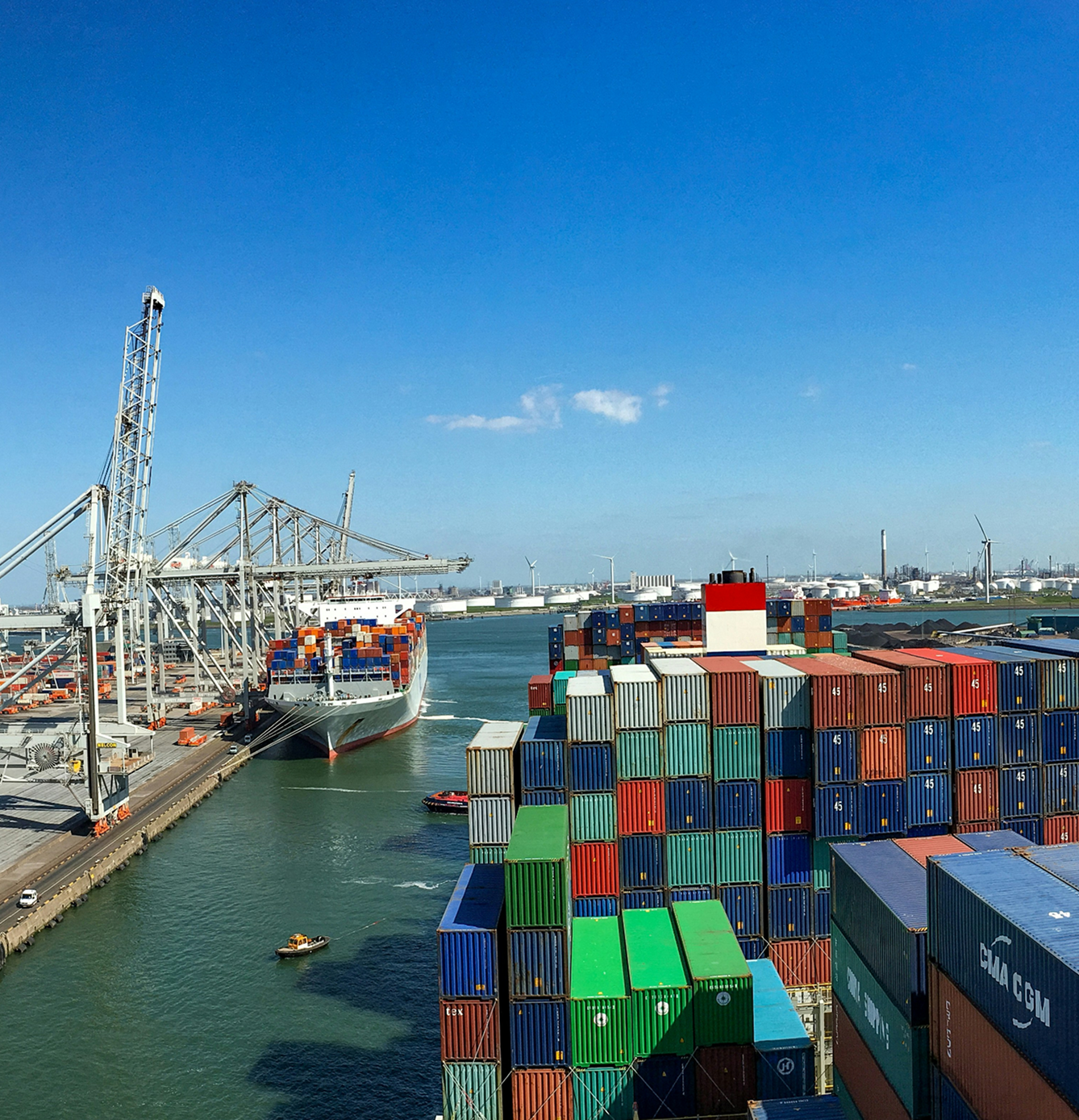Large cargo ships docked at a port with numerous colorful shipping containers stacked high.