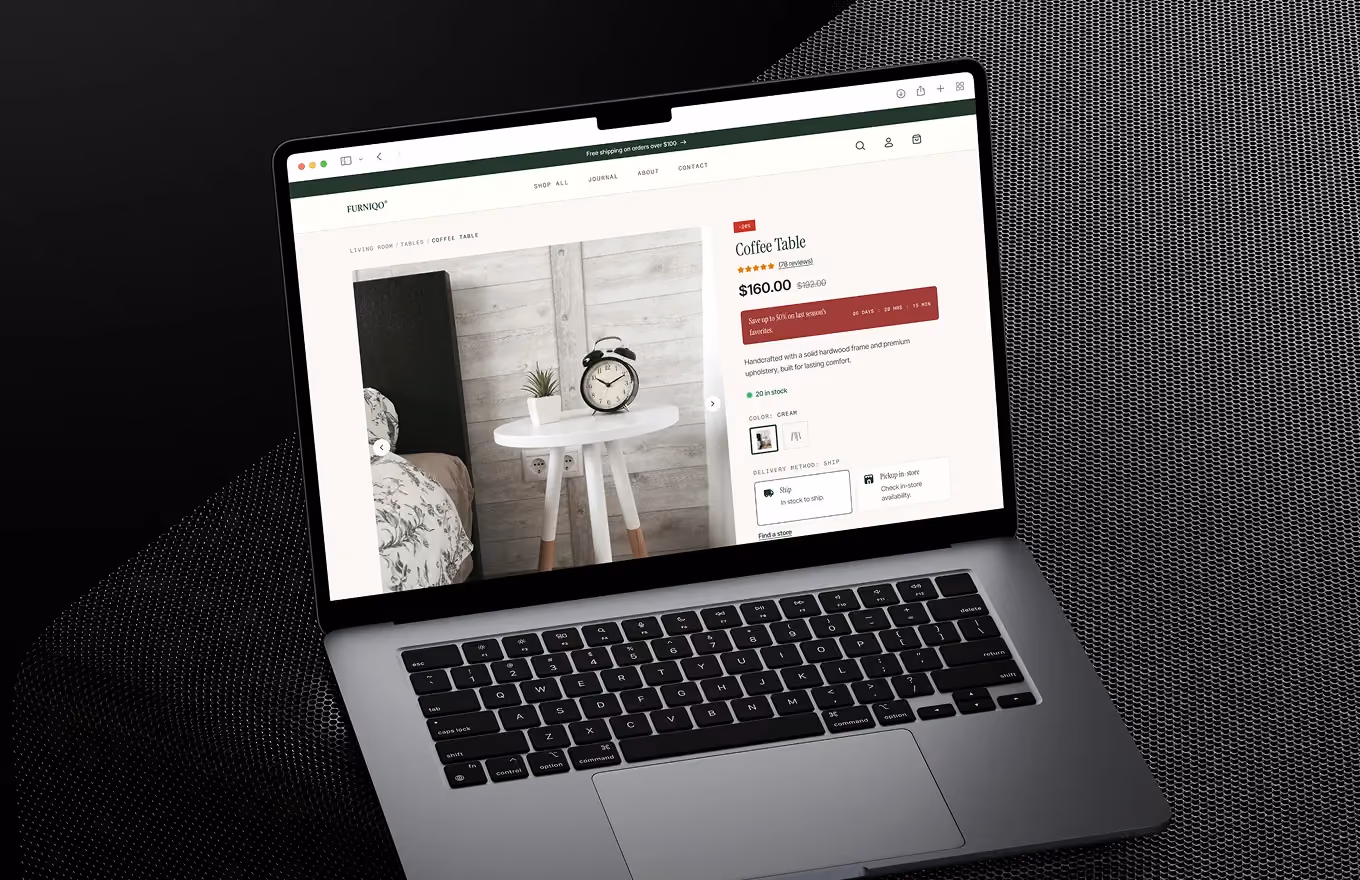 MacBook laptop showing an online store page for a white coffee table with clock and plant.