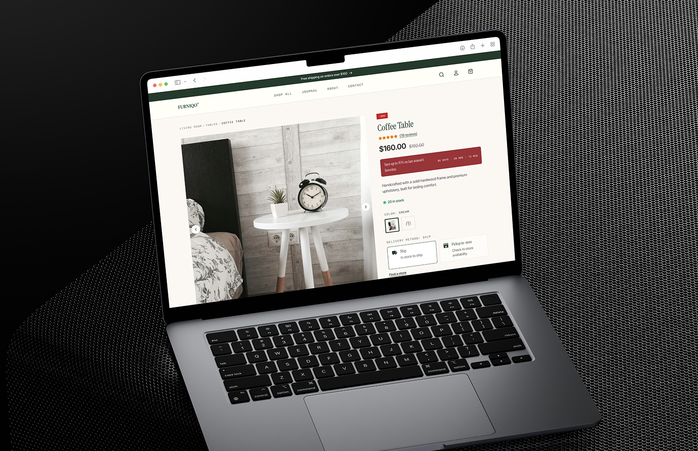 MacBook laptop showing an online store page for a white coffee table with clock and plant.