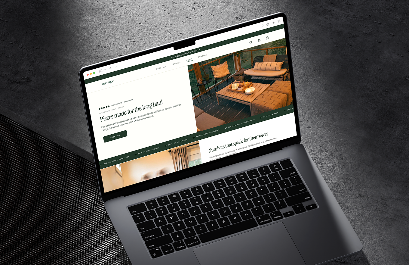 MacBook Pro on textured dark surface showing a furniture website with images and text about quality pieces.