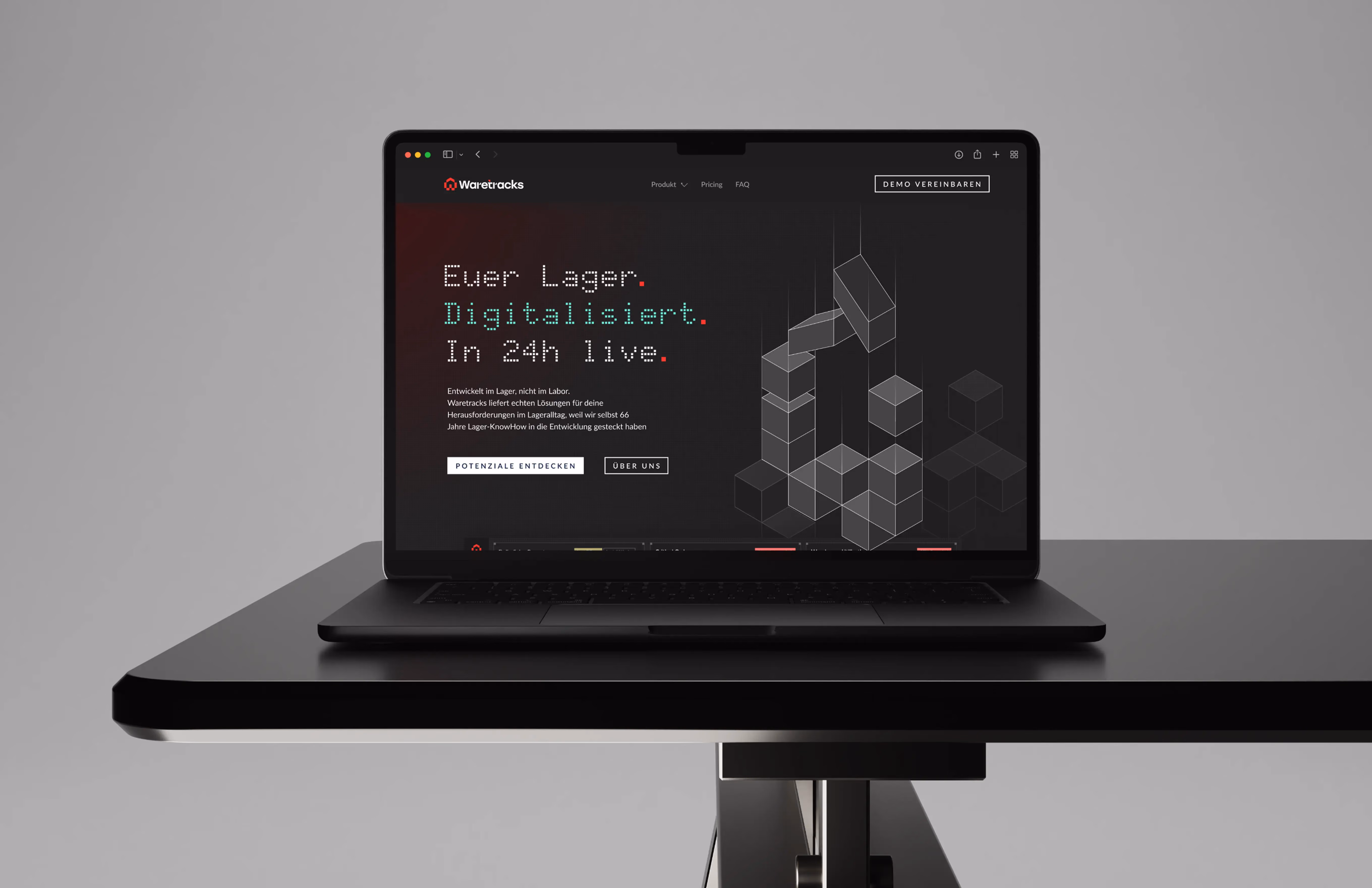 Black laptop on a table displaying Waretracks website with German text and geometric cube graphics.